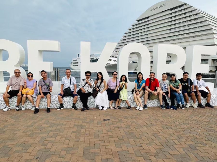 Guests seated on the BE KOBE monument at Kobe harbor