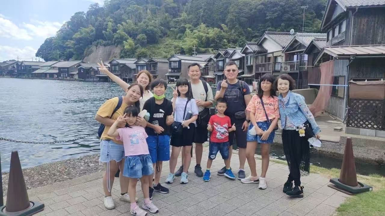 A tour group smiling at the Ine boathouses in northern Kyoto